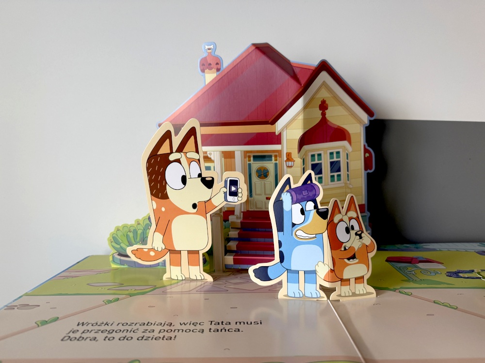 Bluey i Bingo w przestrzennej scence z książki Bluey Wielki Pop Up – dom rodziny Łączków