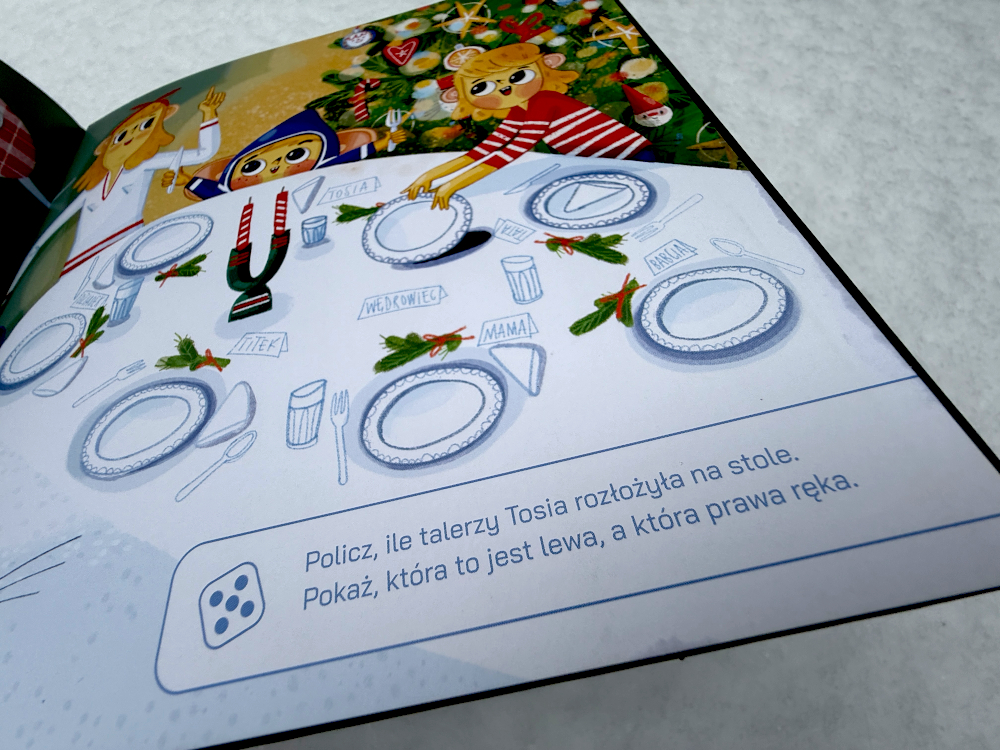 Ilustracja z książki Titek i magia świąt: świątecznie nakryty stół przygotowany przez dzieci. Widać talerze, sztućce i karteczki z imionami gości. Titek i Tosia stoją przy choince, a na dole strony znajduje się polecenie zachęcające dzieci do liczenia talerzy.