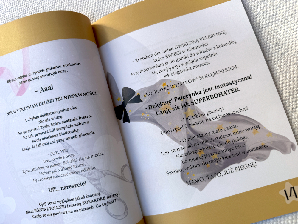 Ilustracja z wnętrza książki „Przygody kłębuszka spod łóżka” przedstawiająca scenę szykowania pelerynki dla Kłębuszka; na stronach widać dialogi i pastelowe grafiki oraz gwiezdną pelerynkę bohatera.