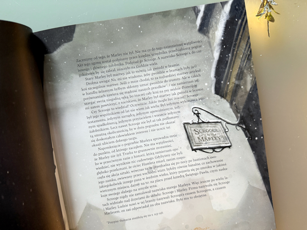 Otwarta strona książki Opowieść wigilijna Charlesa Dickensa z tekstem i mroczną, zimową oprawą graficzną