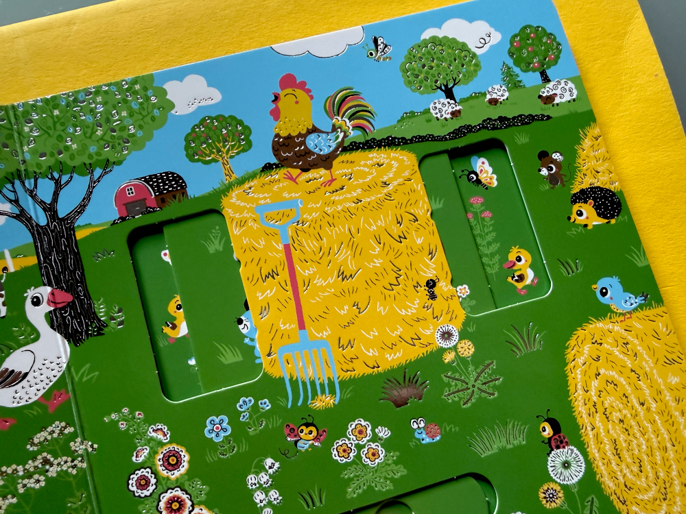 Rozkładówka z kogutem na stogu siana, przesuwanym elementem i zwierzętami gospodarskimi na kolorowej farmie.