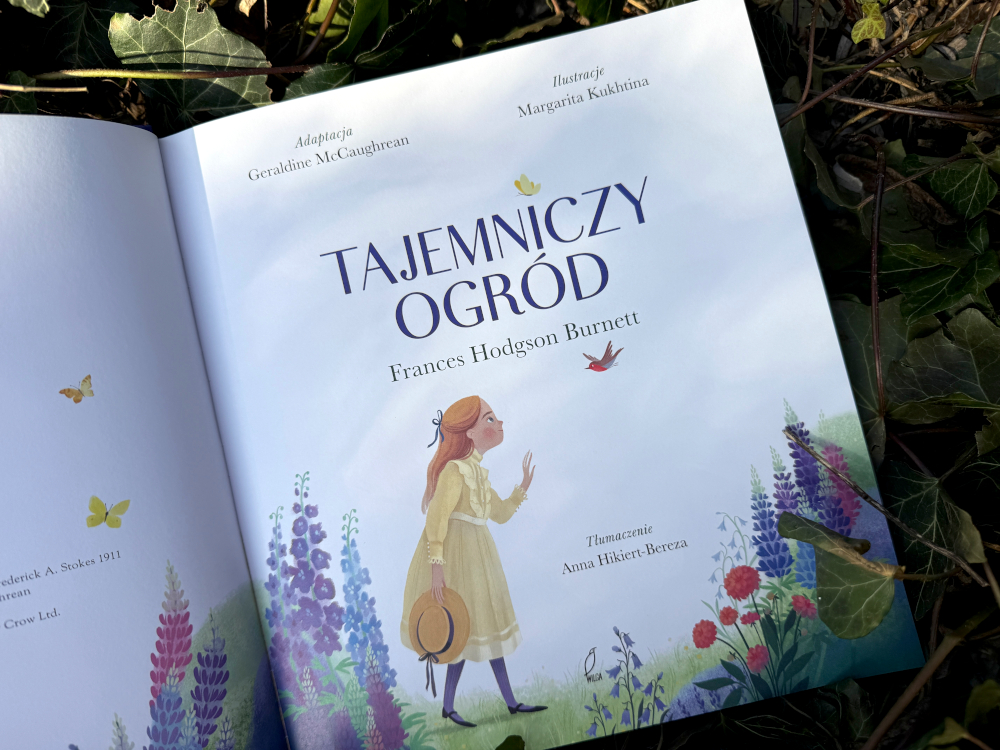 Otwarte wydanie książki Tajemniczy ogród z ilustracją Mary Lennox wśród kwiatów i widoczną stroną tytułową