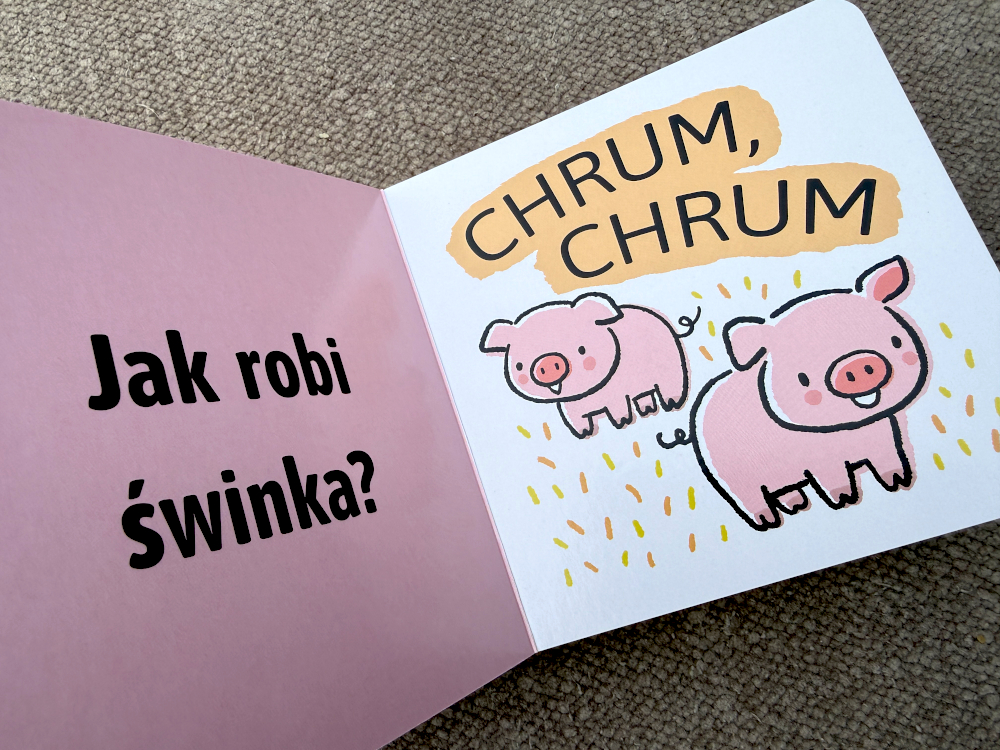Książka kartonowa dla dzieci otwarta na stronie ze świnką i dźwiękiem chrum, prosta ilustracja i pytanie o odgłos zwierzęcia
