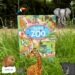 Okładka książki Dzień w zoo dla najmłodszych dzieci z kolorową ilustracją zwierząt i odwiedzających ogród zoologiczny