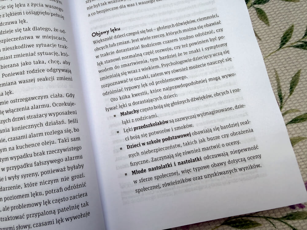 Strona książki omawiająca typowe objawy lęku u dzieci w różnych grupach wiekowych.