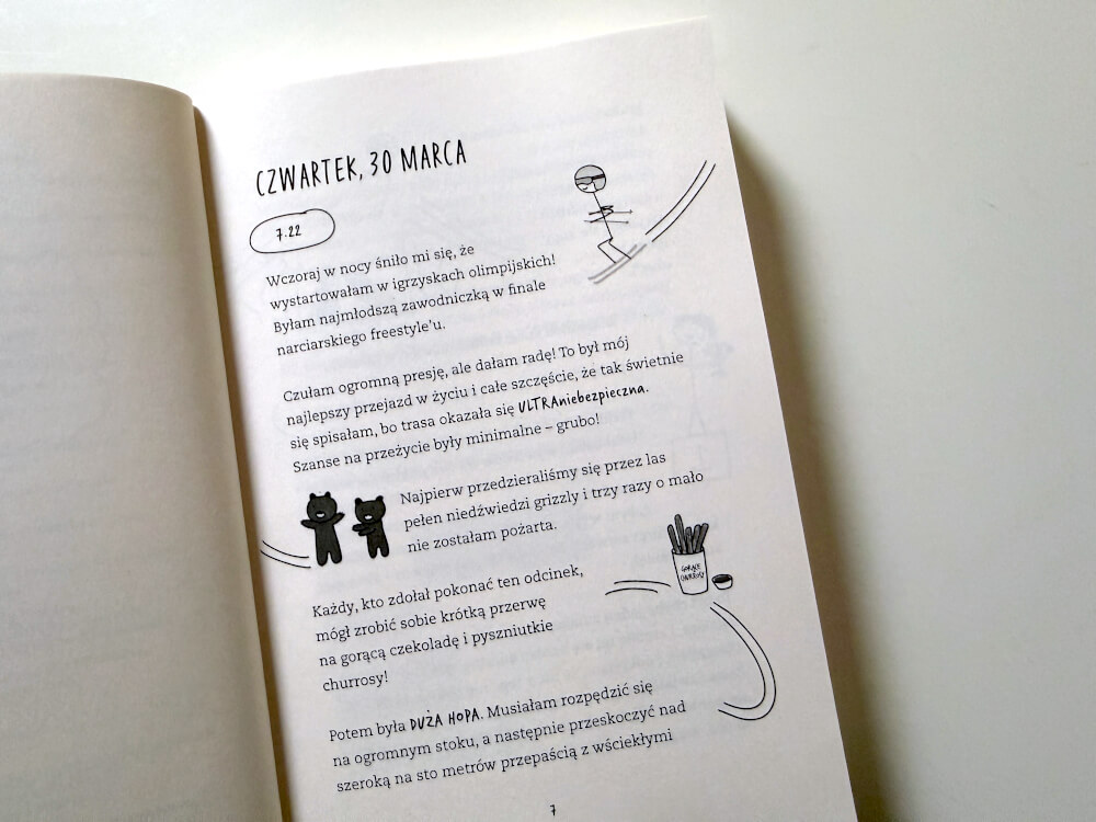 Otwarta książka Lottie Brooks ze śmiesznymi rysunkami i fragmentem o jeździe na nartach.
