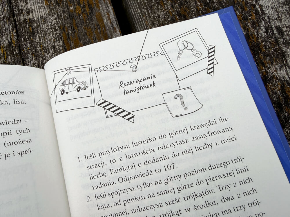 Strona z nagłówkiem Rozwiązania łamigłówek, zawierająca dwie miniaturowe ilustracje: samochodu i pęku kluczy. Poniżej tekst z instrukcją: Jeśli przyłożysz lusterko do górnej krawędzi, z łatwością odczytasz.