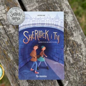 ￼Niebieska okładka książki Sherlock i Ty. Tajemnica zaginionego domu z ilustracją dwójki dzieci w tunelu na tle Londynu, leżąca na drewnianej ławce. W rogu znaczek wiek 9+