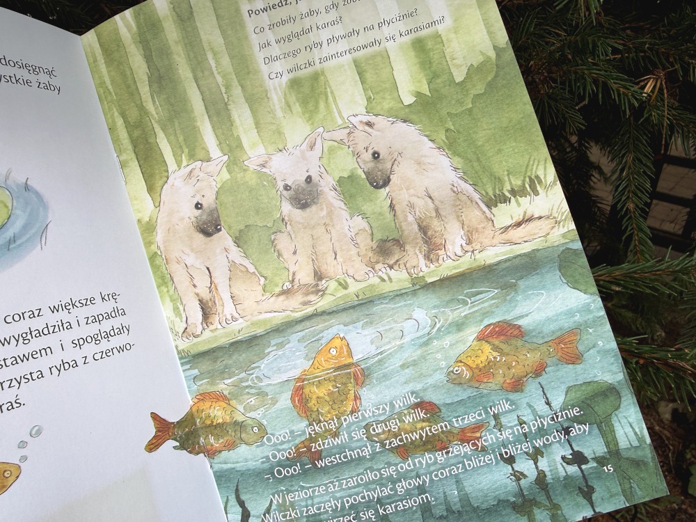 Strona książki Wilcze uszy ukazująca małe wilczki i ryby w wodzie