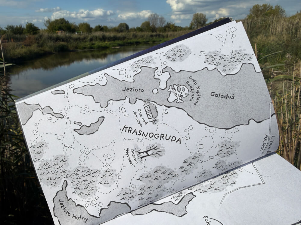 Rozkładówka książki z czarno-białą mapą okolic Krasnogrudy i jeziora Hołny.