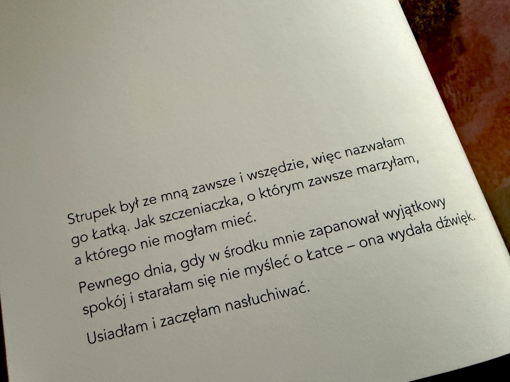 Otwarta strona książki Łatka i ja z fragmentem tekstu opisującym bliską relację ze strupkiem.